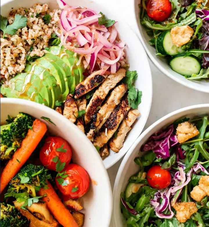 Colorful chicken grain bowls, roasted vegetables, and fresh salads arranged for a week of dinners